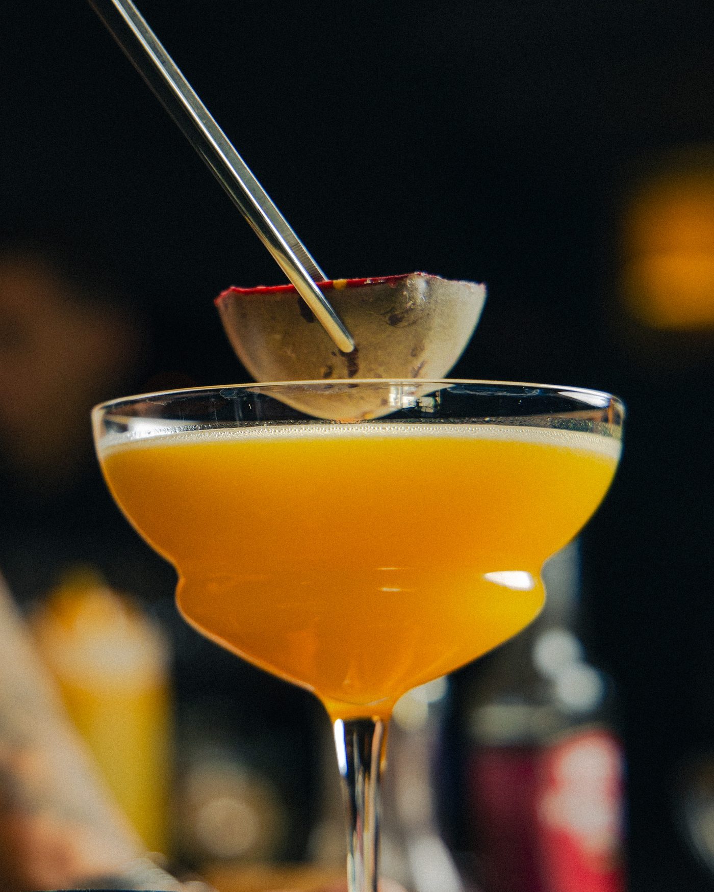 Cocktail orange en coupe, garni au couteau, sur le bar de Dario