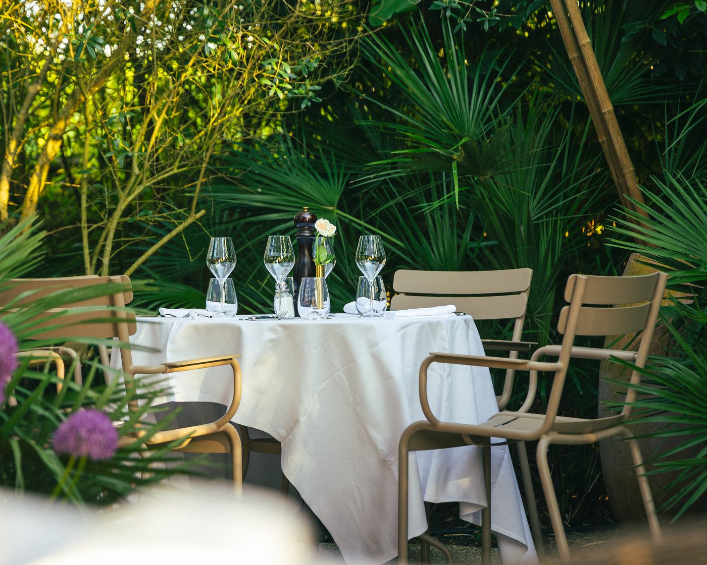 Les tables du jardin de la Villa Léonard, dressées de blanc dans la verdure