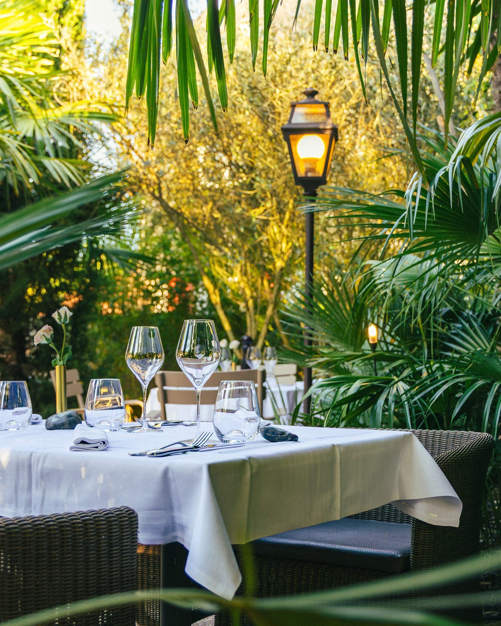Une table dressée dans le jardin de la Villa Léonard, nappes blanches sous les palmiers
